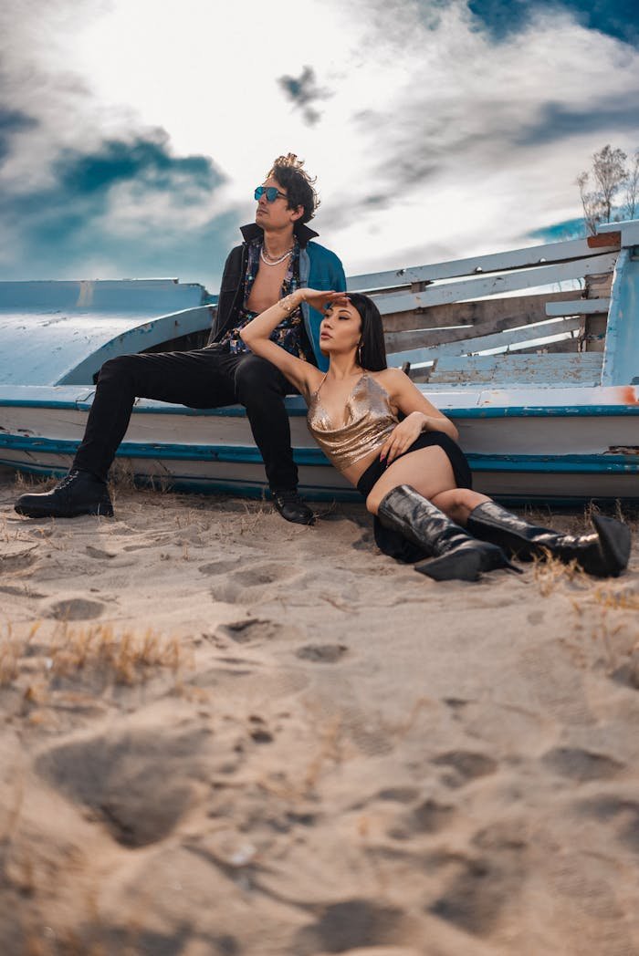 Two people sitting on the beach next to a boat